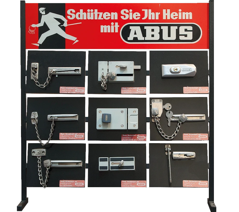 Egy állvány „Védje otthonát az ABUS termékekkel” feliratú plakáttal, alatta különböző ABUS ajtó másodzárakkal © ABUS